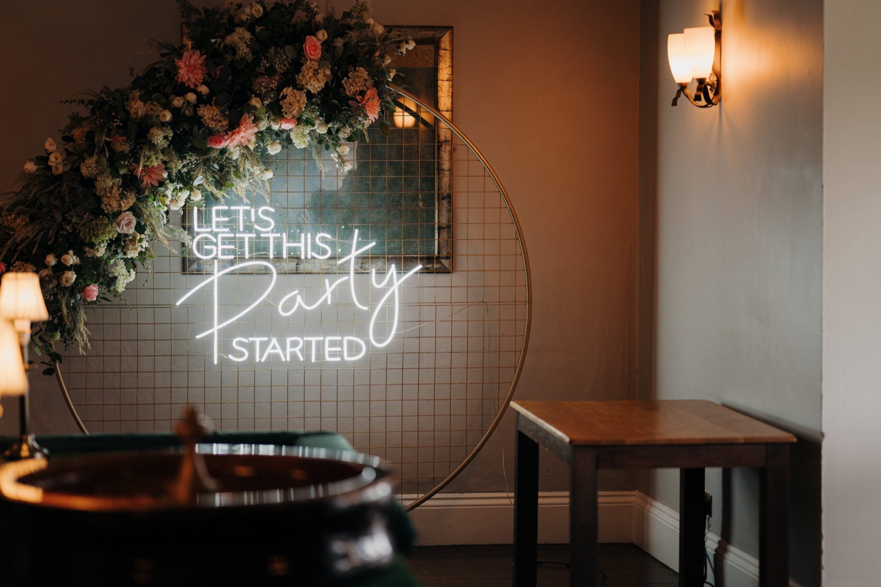 A celebration setup with neon signage and floral arch